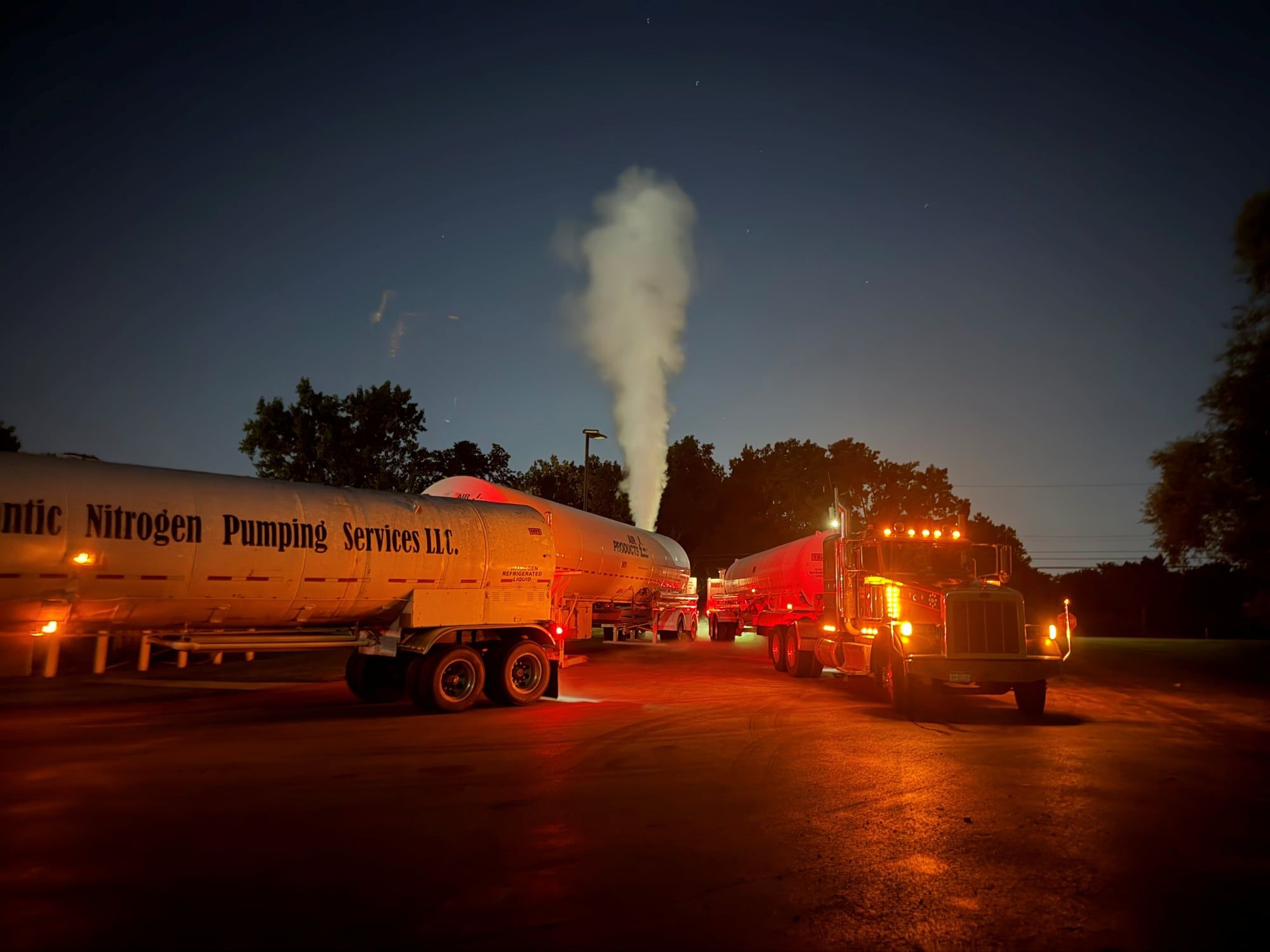 Atlantic Nitrogen Pumping Services transports lit up at night with a nitrogen vent plume rising behind them